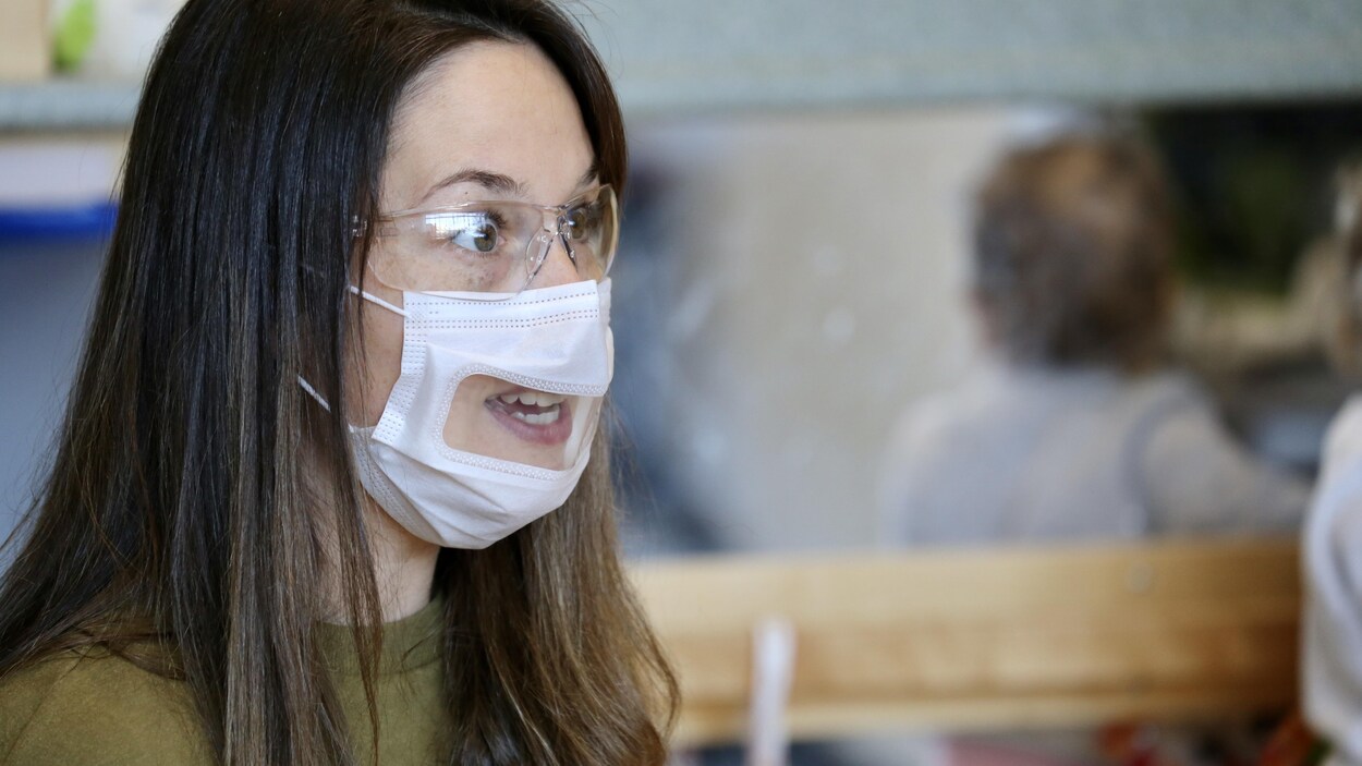 Une femme porte un masque à fenêtre transparente. 