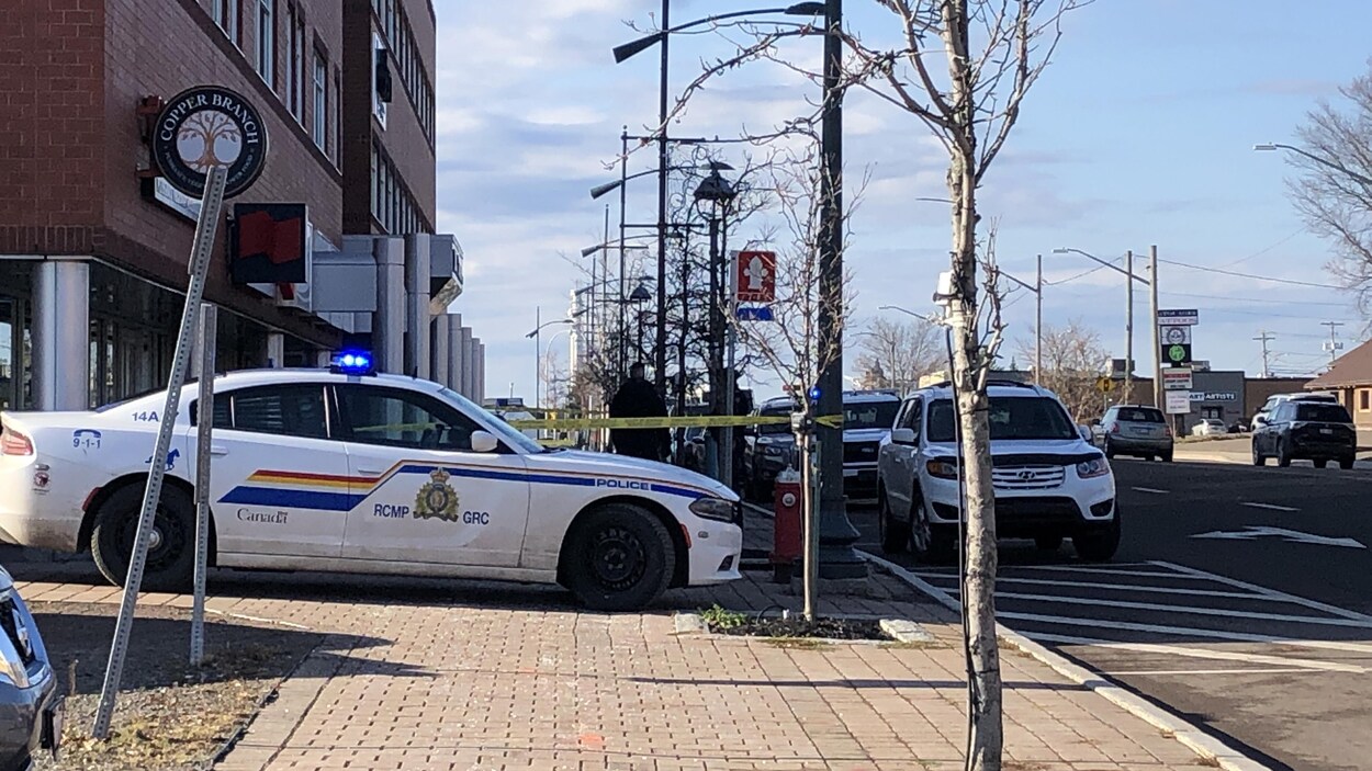 Voiture de police sur le trottoir et cordon jaune policier qui bloque le trottoir.
