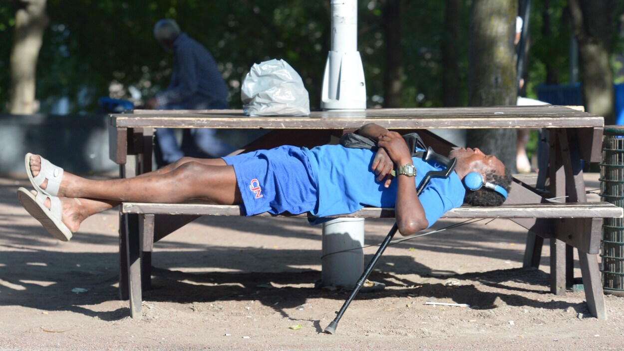 Un homme allongé sur un banc dans un parc.