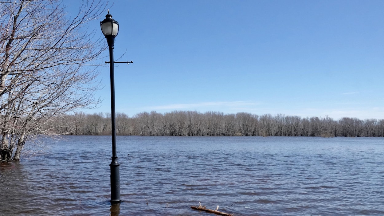 L'eau d'une rivière monte jusqu'au pied d'un lampadaire.