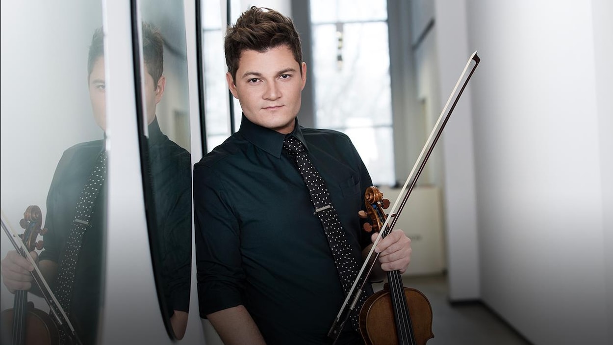 Le violoniste Alexandre Da Costa appuyé contre un mur sur lequel deux miroirs reflètent partiellement son visage