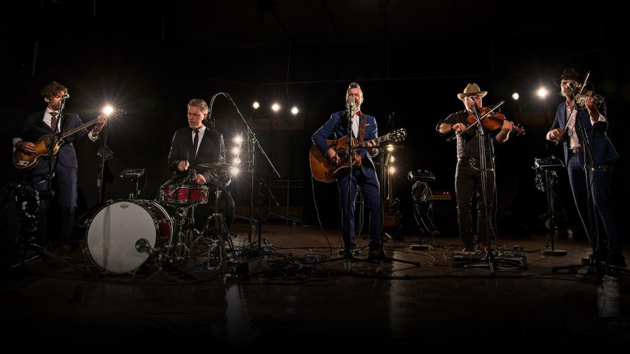 Un à côté de l'autre, de gauche à droite : Kevin Mcintyre à la basse, Jean-François Breau à la batterie, Jonathan Painchaud à la guitare, Éloi Painchaud au violon et George Belliveau, aussi au violon.