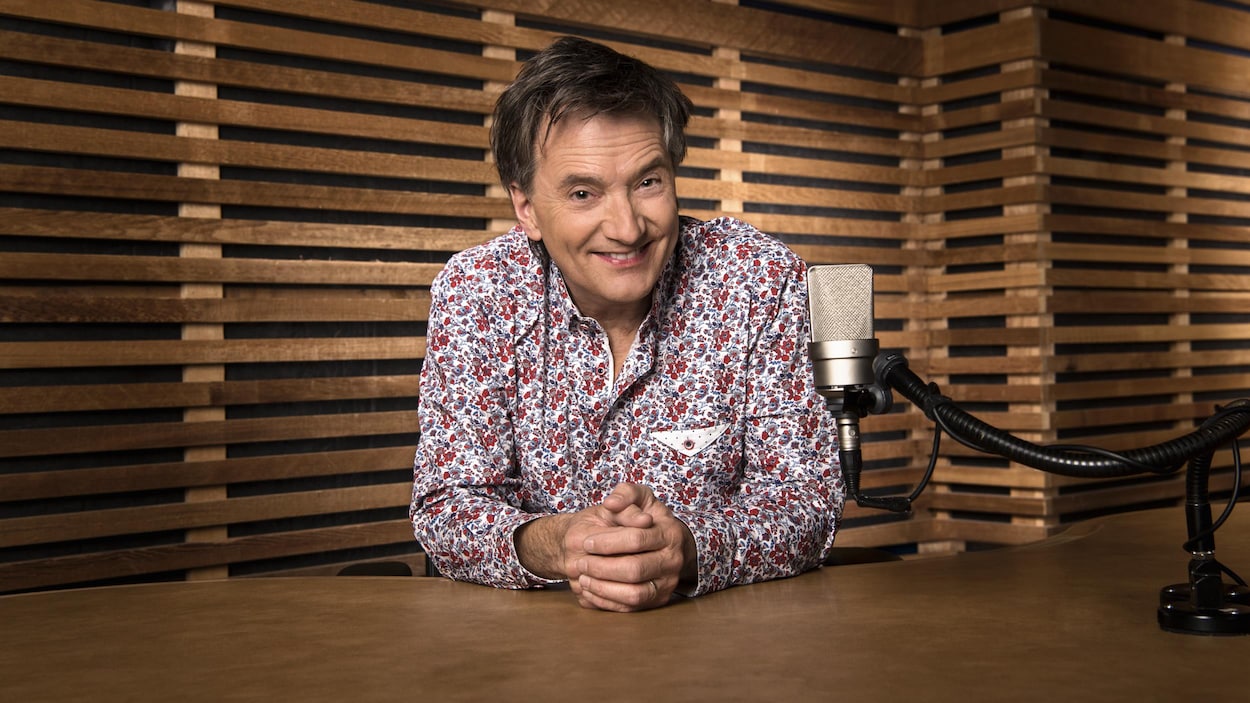 Dans un studio d'ICI Musique, Francis Reddy, souriant, est devant un micro.