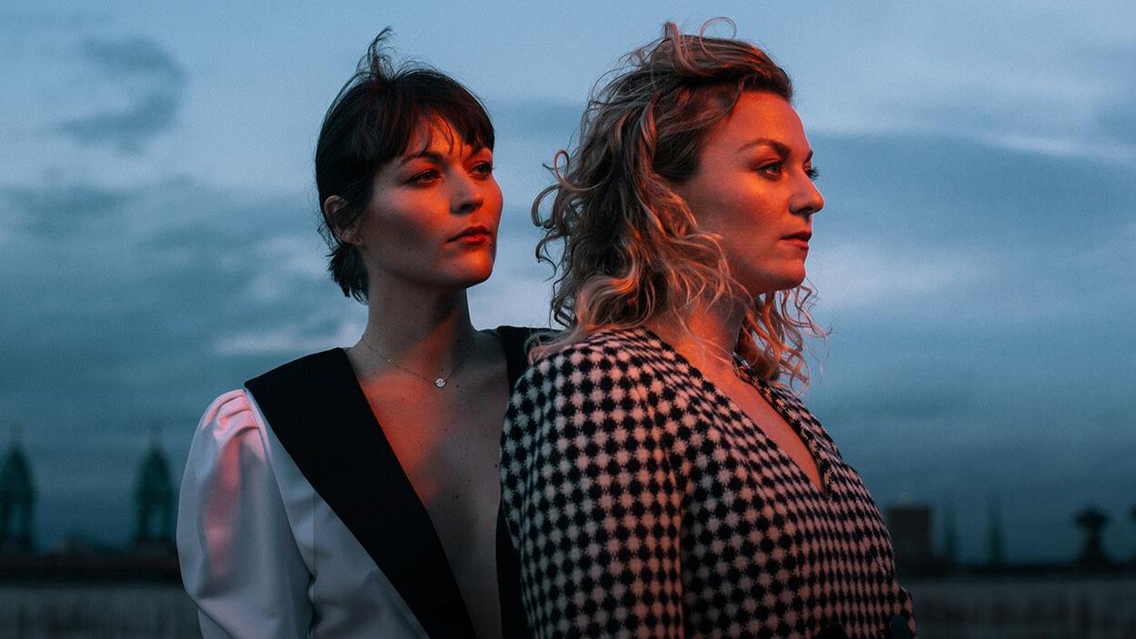 Les soeurs Boulay debout sur un toit regardent à droite.