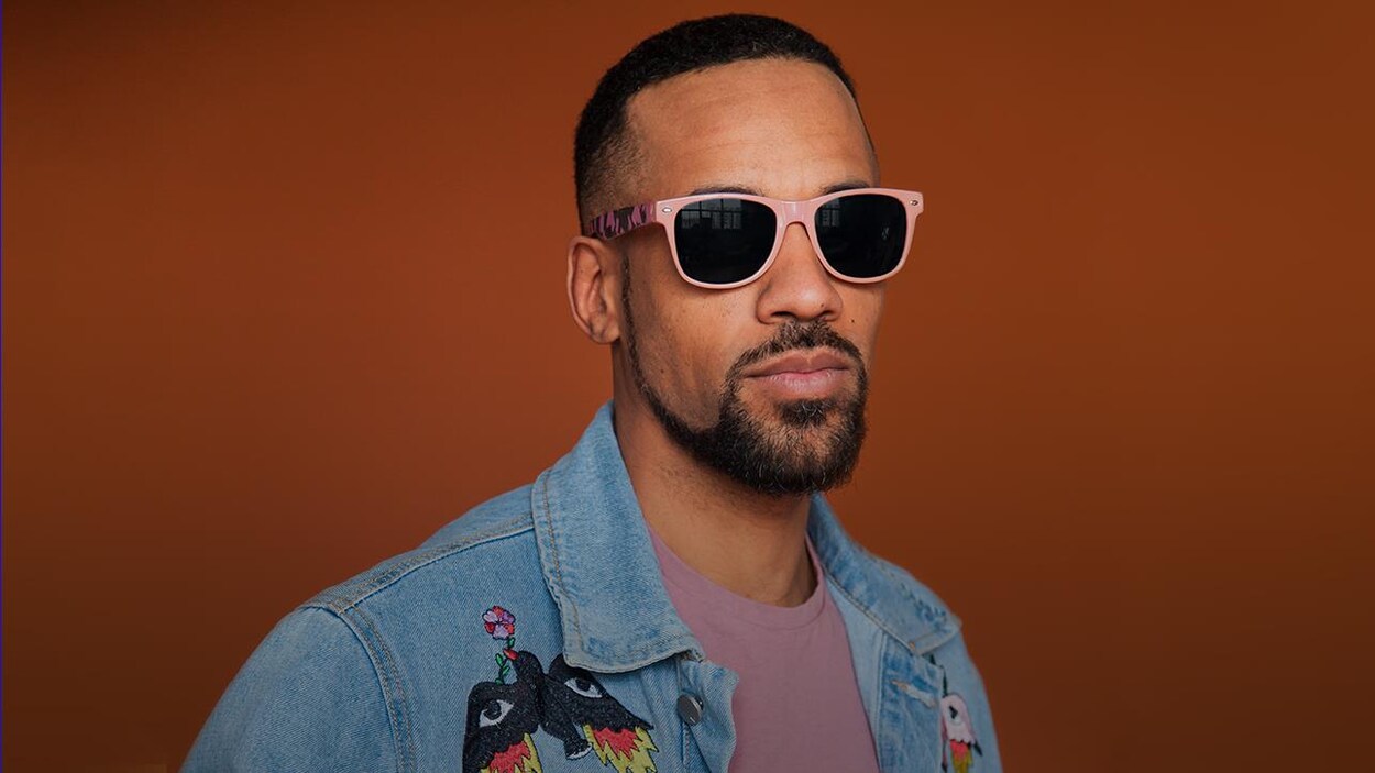 Le rappeur KNLO pose avec ses lunettes fumées.