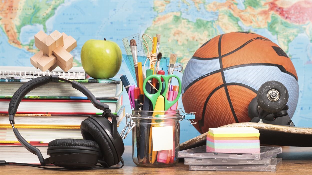 Un pupitre avec un ballon de baseketball et des fournitures scolaires.