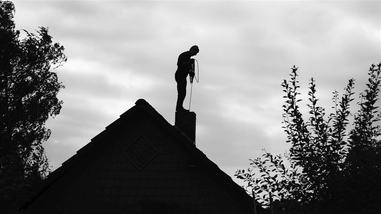 Un ramoneur sur le toit d'une maison.