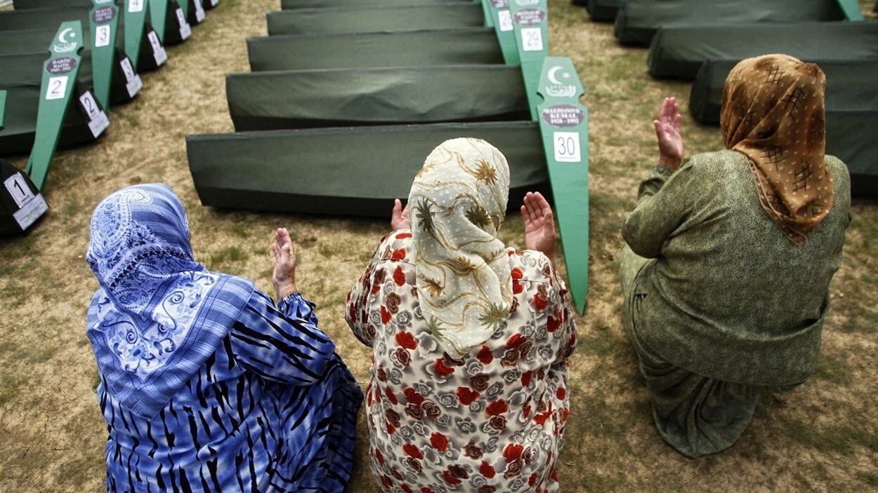Des femmes bosniaques musulmanes prient devant des cercueils. Des femmes bosniaques musulmanes prient devant des cercueils.