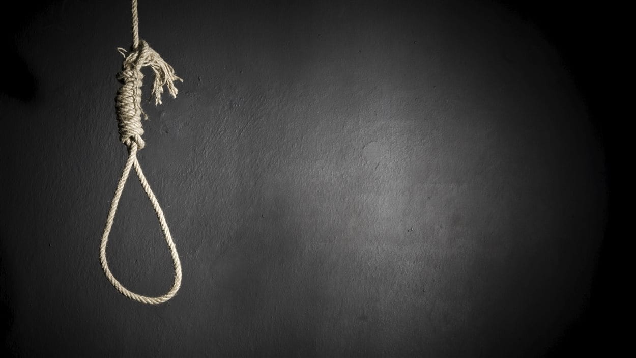 Une corde nouée, prête pour la pendaison, sur fond noir.