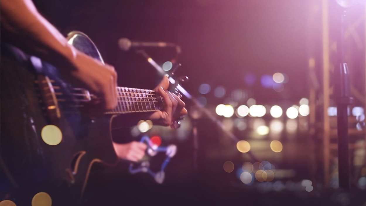 Un musicien joue de la guitare sur scène.