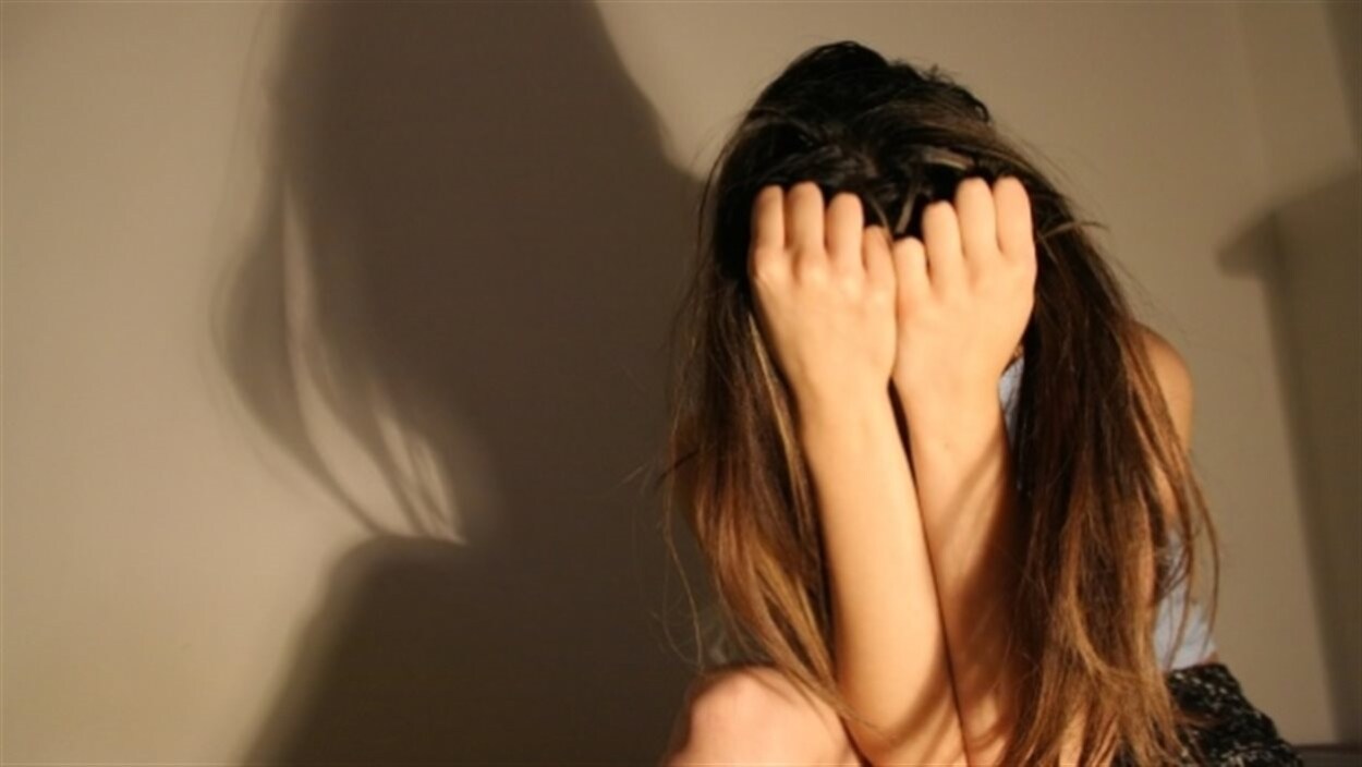 Une jeune femme aux cheveux longs se cache le visage.