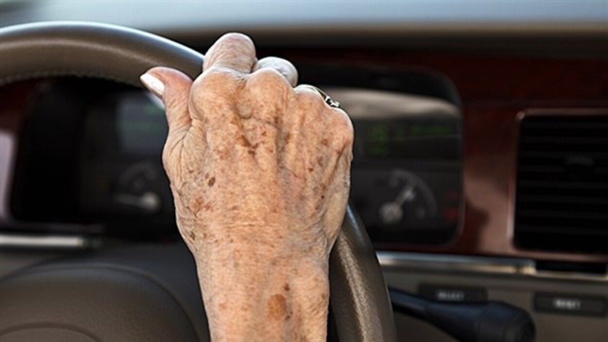 Main d'une personne âgée sur un volant.