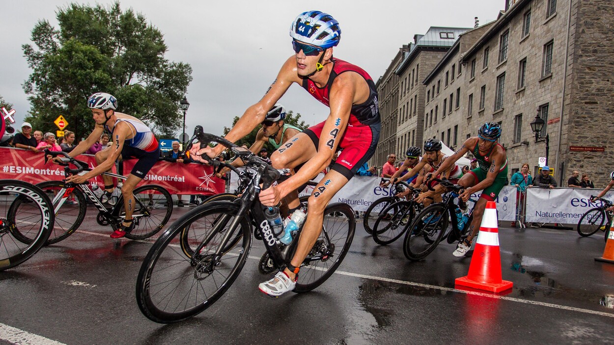 Le Québécois négocie un virage en vélo dans les rues de Montréal avec d'autres athlètes.