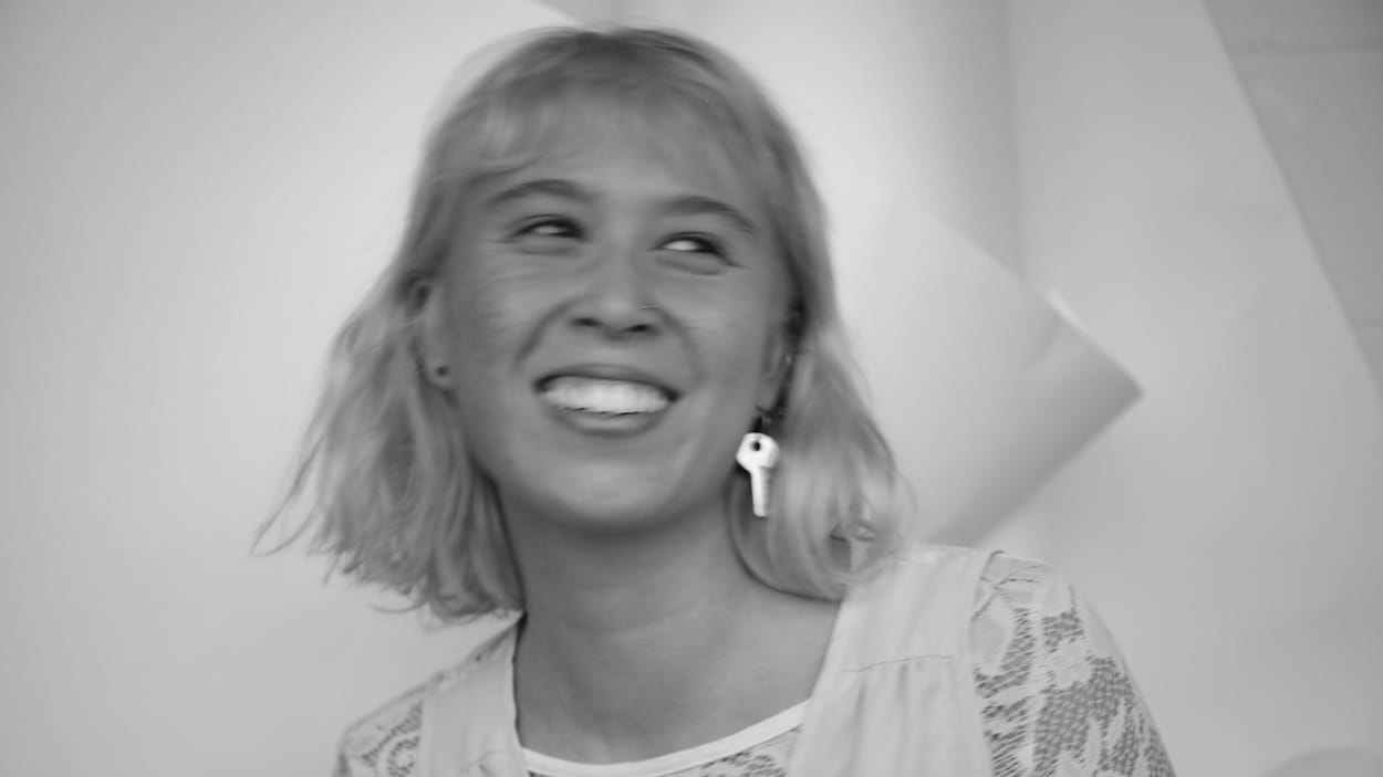 Elle sourit à la caméra.