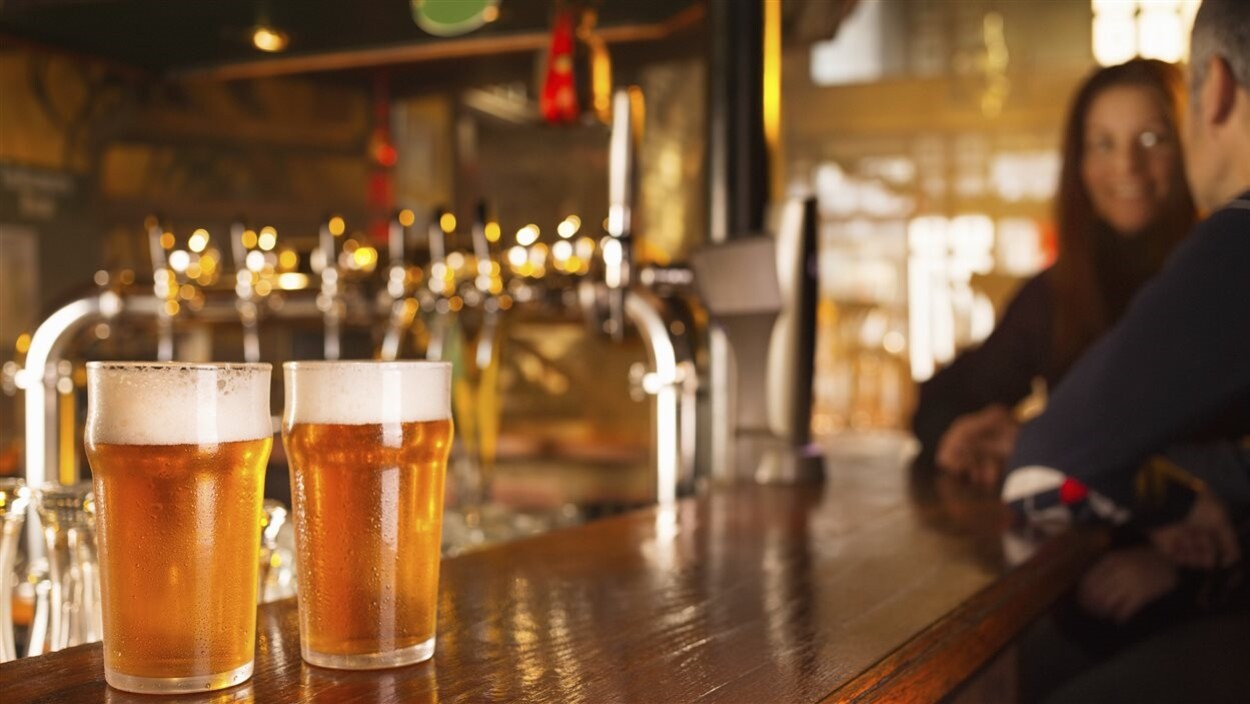 Deux verres sont remplis de bière sur un comptoir dans un bar.