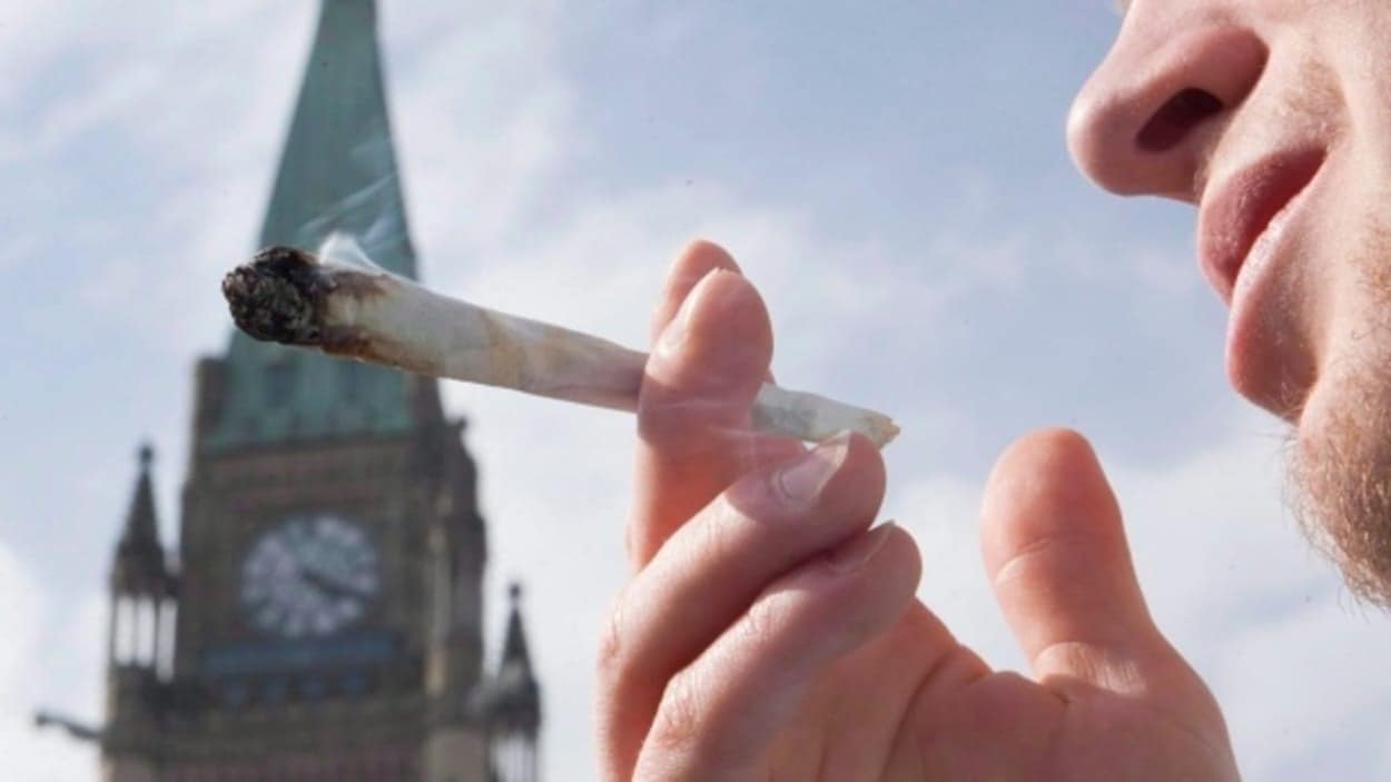 Un homme fume du cannabis devant la tour de la Paix, à Ottawa.