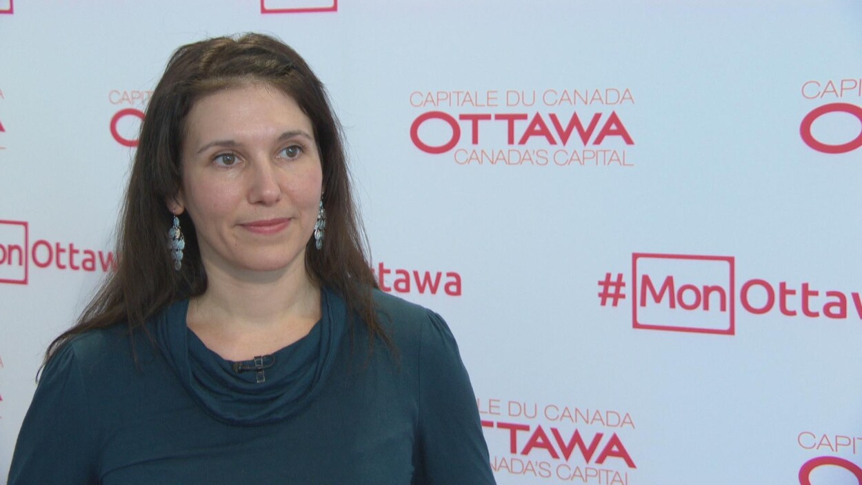 Catherine Callary en entrevue devant un fond blanc portant l'inscription « capitale du Canada, Ottawa ».