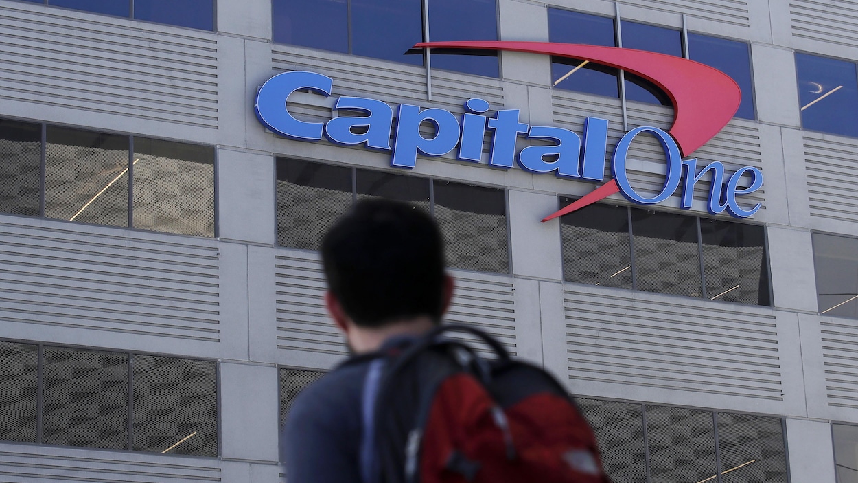 Un homme regarde au loin l'enseigne de Capital One sur un édifice.