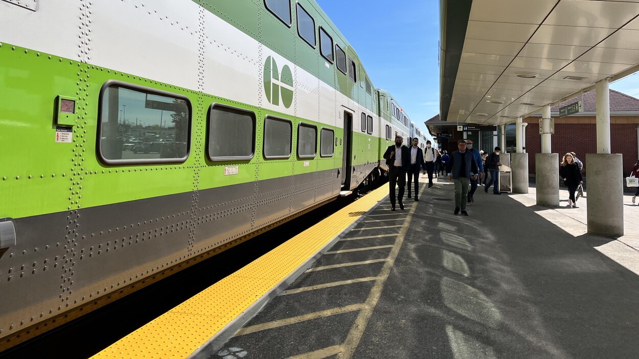 Un train en gare avec des passagers qui y descendent.