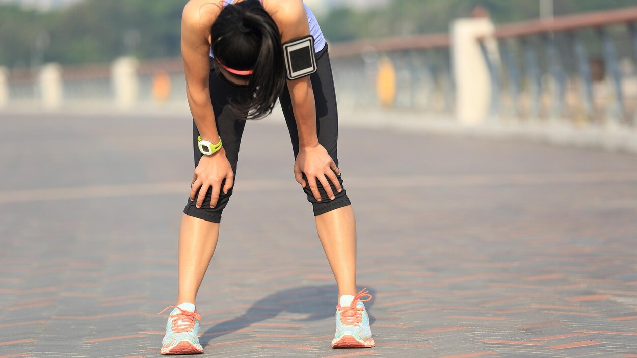 Une femme essoufflée court un marathon.