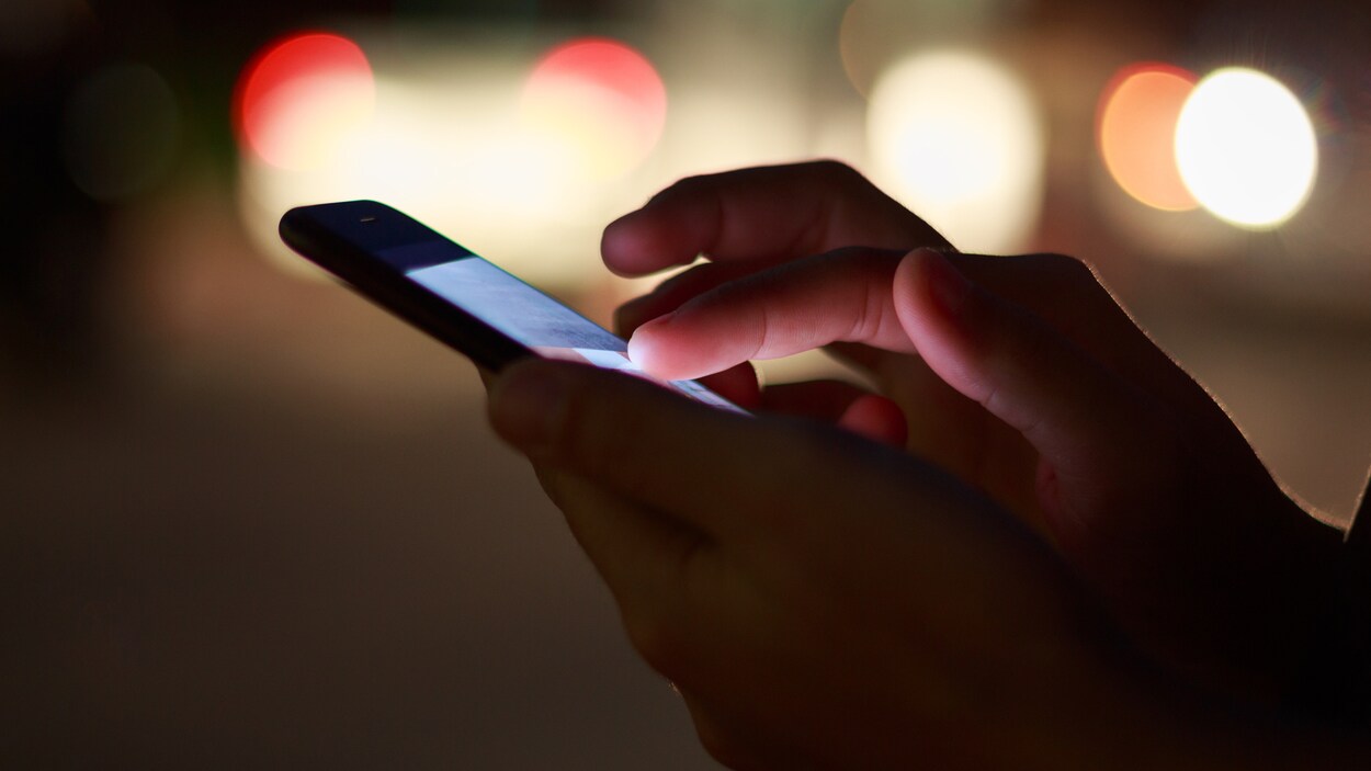 Un homme consulte son téléphone cellulaire.