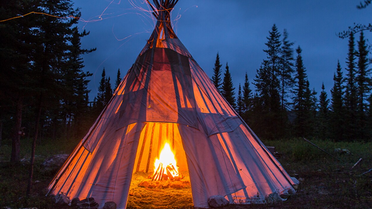 Un feu brûle à l'intérieur d'un tipi, le soir. Un feu brûle à l'intérieur d'un tipi, le soir.