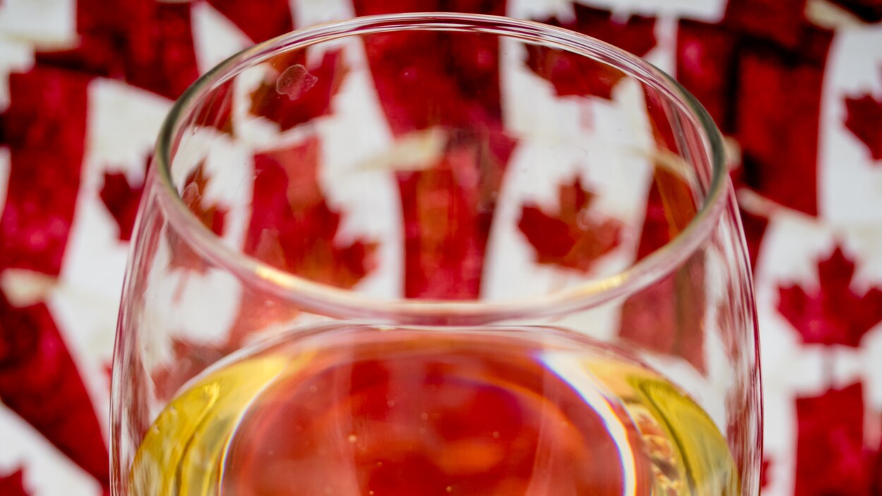 Un verre de vin blanc devant des drapeaux canadiens. Un verre de vin blanc devant des drapeaux canadiens.