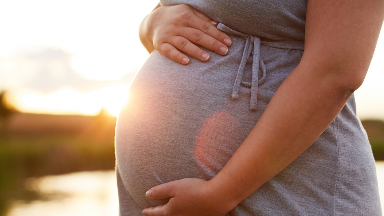 Une femme enceinte devant un coucher de soleil.