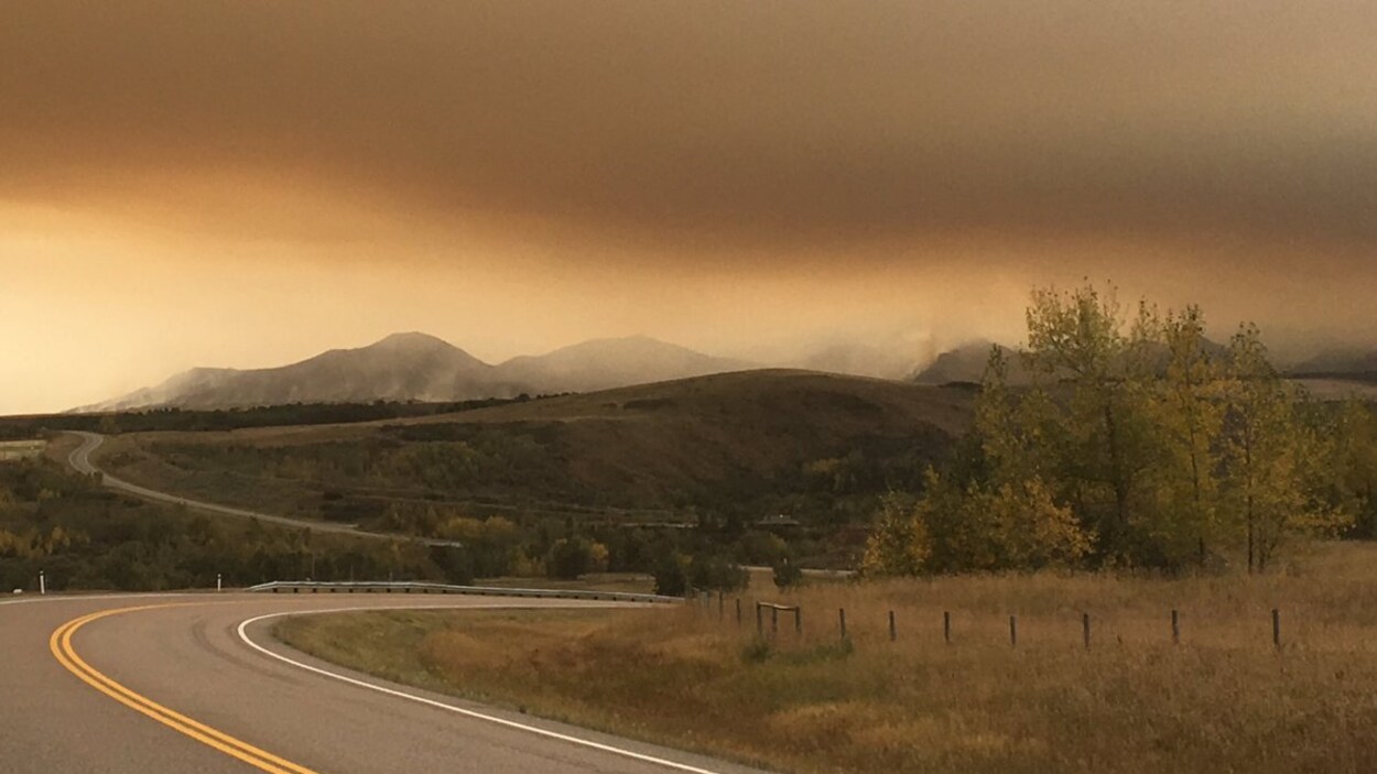 Une route déserte sous un ciel orangé et plein de fumée en raison du feu de forêt Une route déserte sous un ciel orangé et plein de fumée en raison du feu de forêt