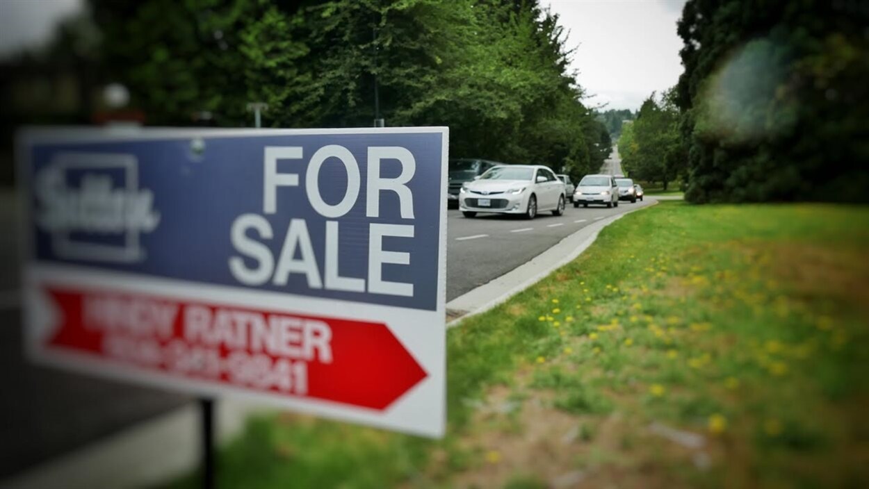Un panneau « À vendre » sur une rue résidentielle.