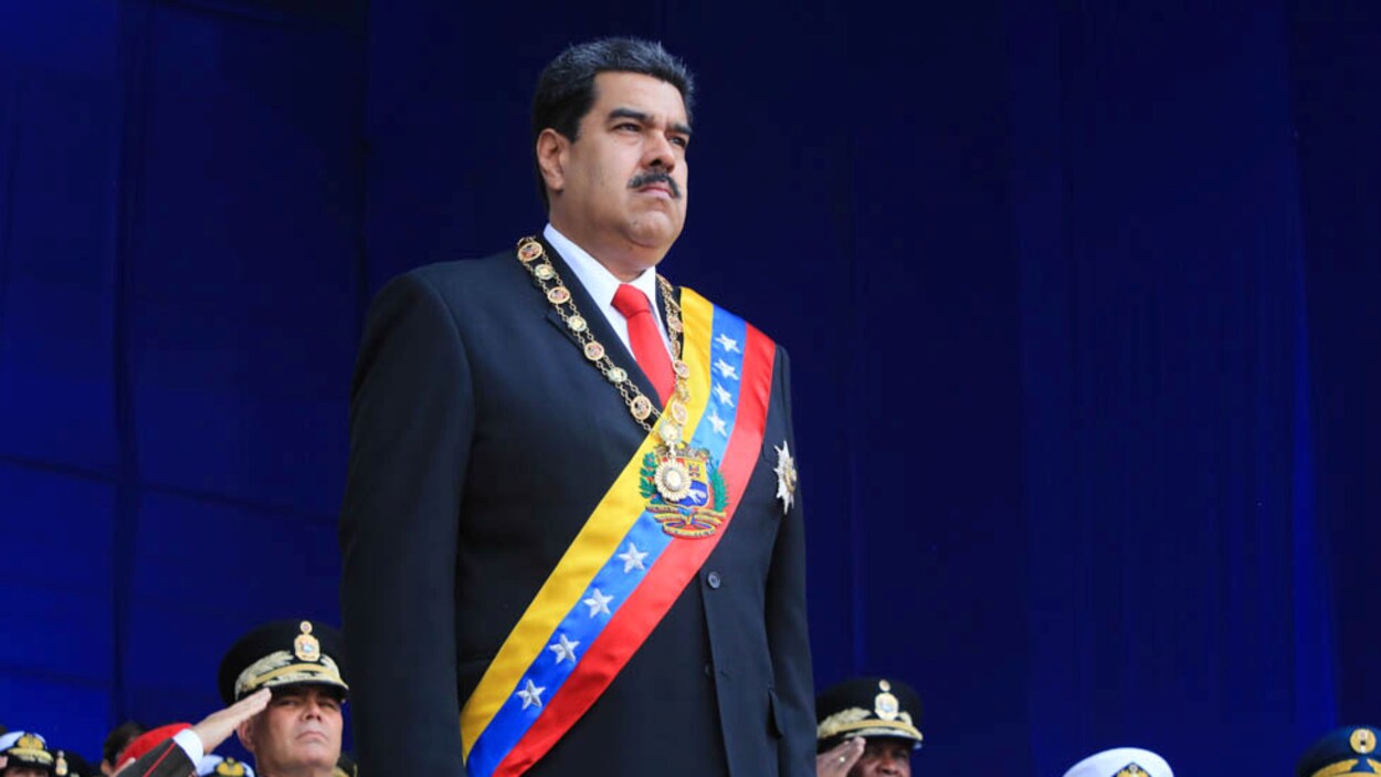 Le président Nicolas Maduro, l'air solennel, se tient sur la scène lors d'un grand événement militaire, à Caracas.