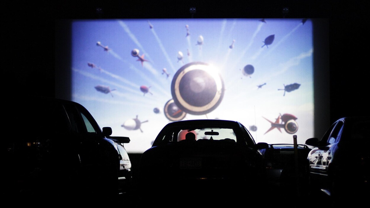 Une personne regarde un film dans sa voiture dans un ciné-parc.