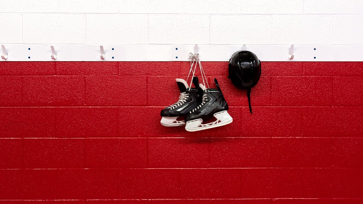 Des patins sont accrochés sur le mur d'un aréna.