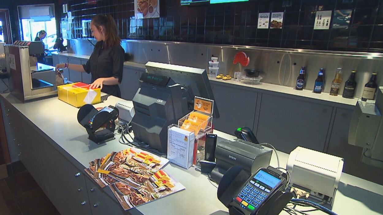 Une jeune femme prépare des commandes pour emporter derrière un comptoir.