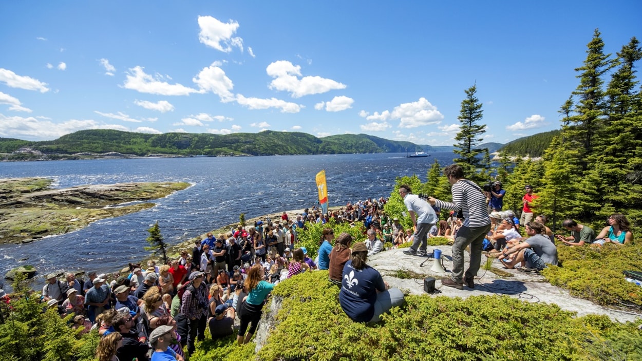 Keith Kouna joue de la guitare devant une foule sur le bord de l'eau.
