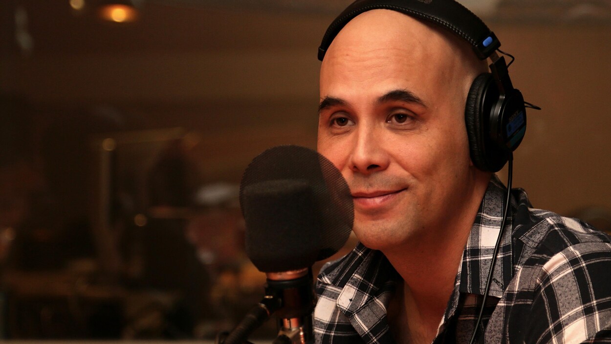 Kim Nguyen esquissant un sourire léger dans un studio de radio.