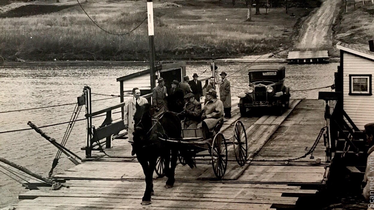 Une charette attelée d'un cheval et une voiture ancienne sur un traversier utilisé pour traverser la rivière Rouge au Manitoba avant les année 1960. 