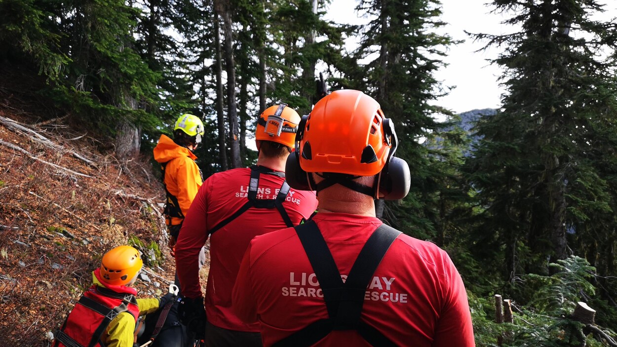 Des hommes et des femmes dans une montagne. Ils sont en train de sauver une personne.