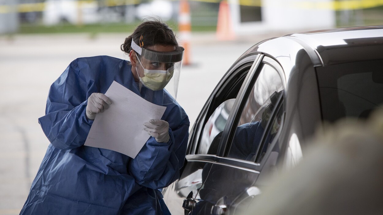 Une infirmière qui fait du dépistage à l'auto fait passer un questionnaire.