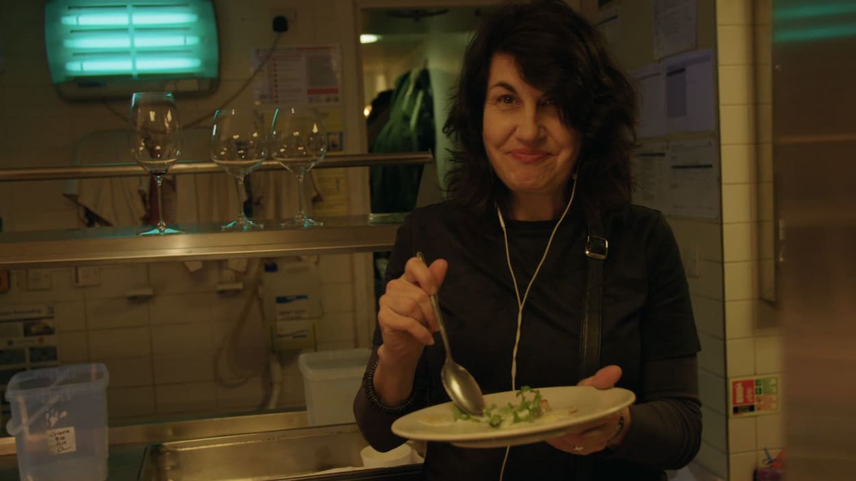 Une dame mange quelque chose dans la cuisine d'un restaurant avec des écouteurs dans les oreilles. Une dame mange quelque chose dans la cuisine d'un restaurant avec des écouteurs dans les oreilles.