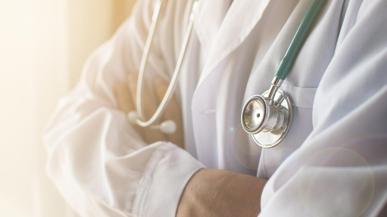 Un médecin portant un stéthoscope se croise les bras.