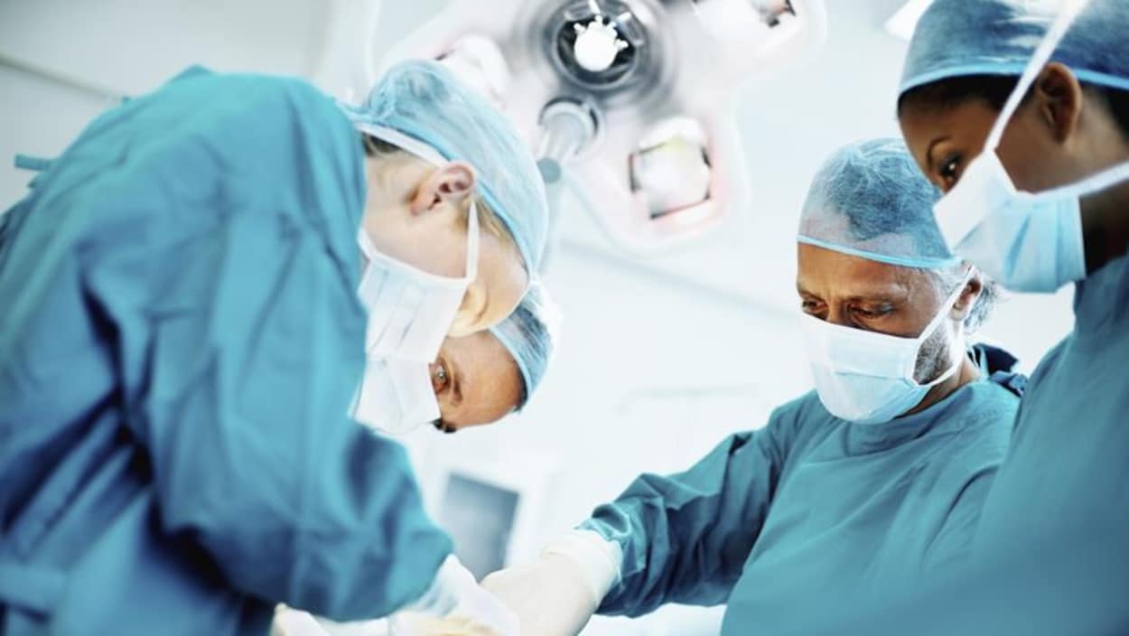 Quatre médecins dans une salle d'opération.