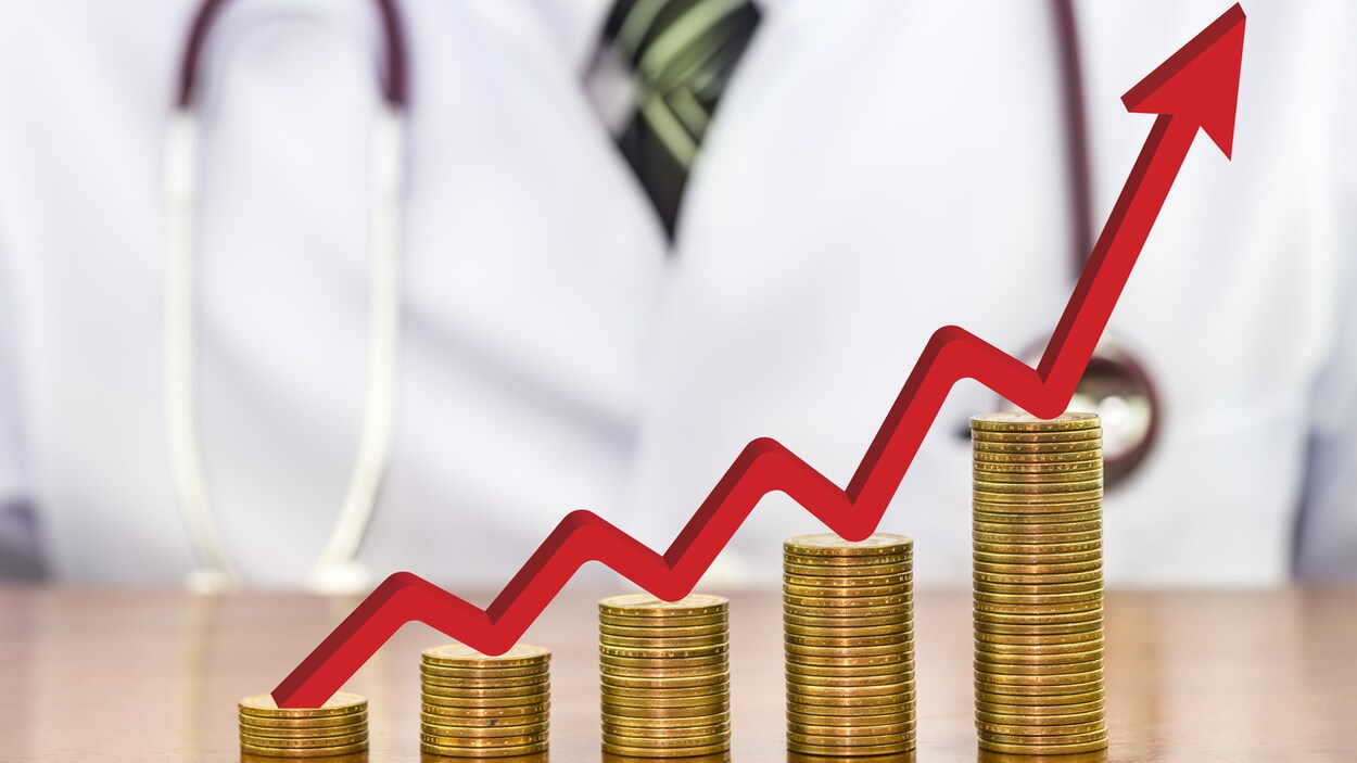 Une flèche rouge par dessus une pile de monnaie. En arrière plan, une personne avec un sarrau blanc et un stéthoscope autour du cou. Une flèche rouge par dessus une pile de monnaie. En arrière plan, une personne avec un sarrau blanc et un stéthoscope autour du cou.