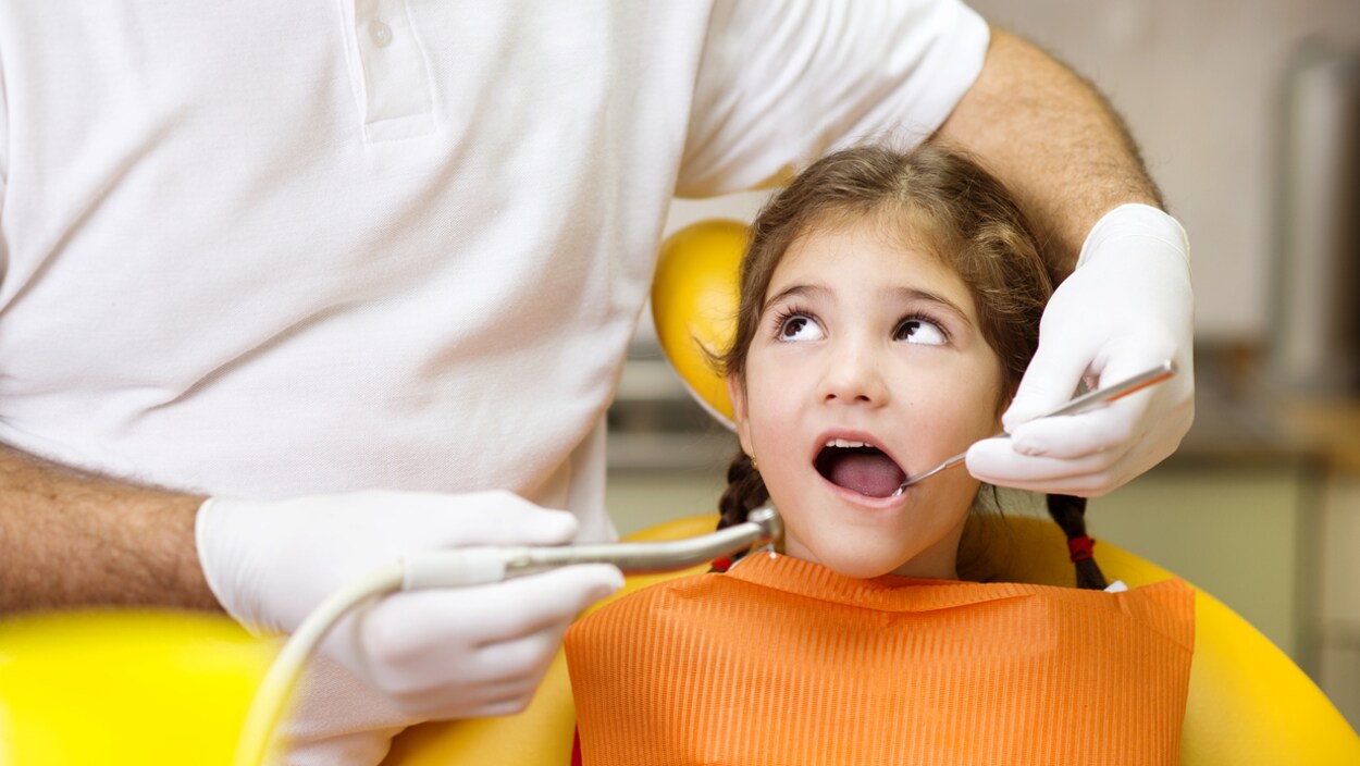 Une petite fille se fait examiner par un dentiste. Une petite fille se fait examiner par un dentiste.
