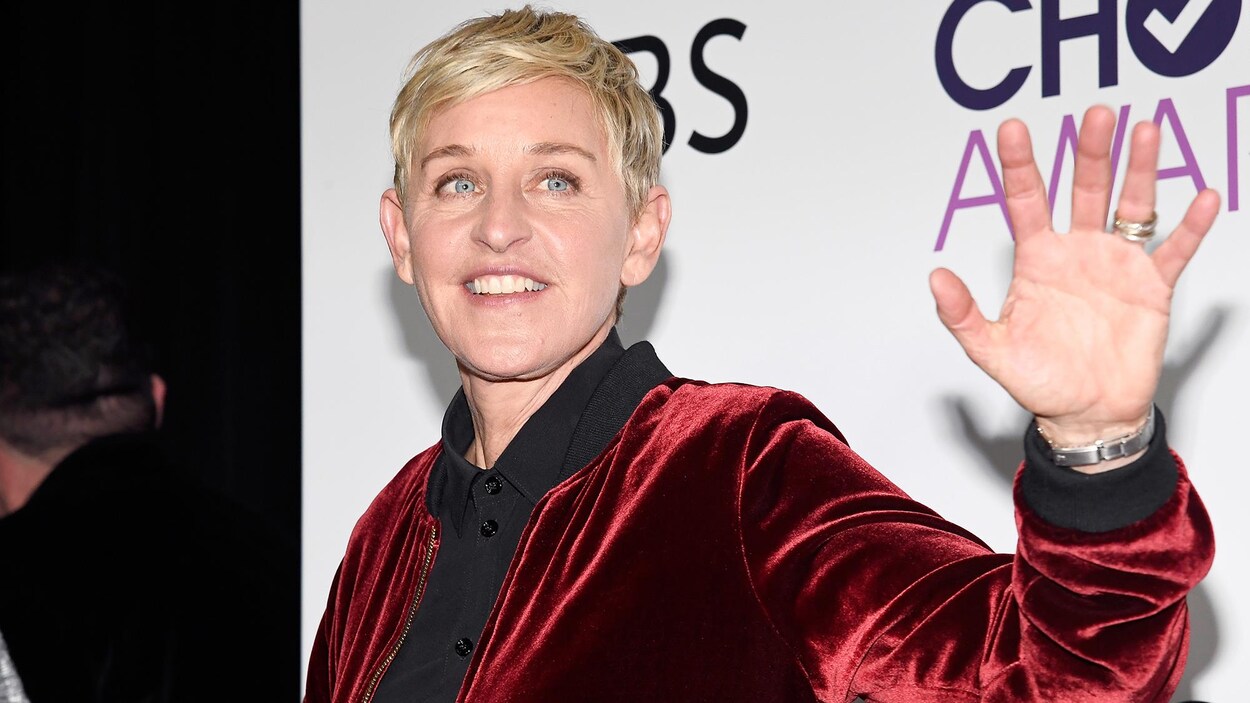 Ellen DeGeneres lève la main à quelqu'un.