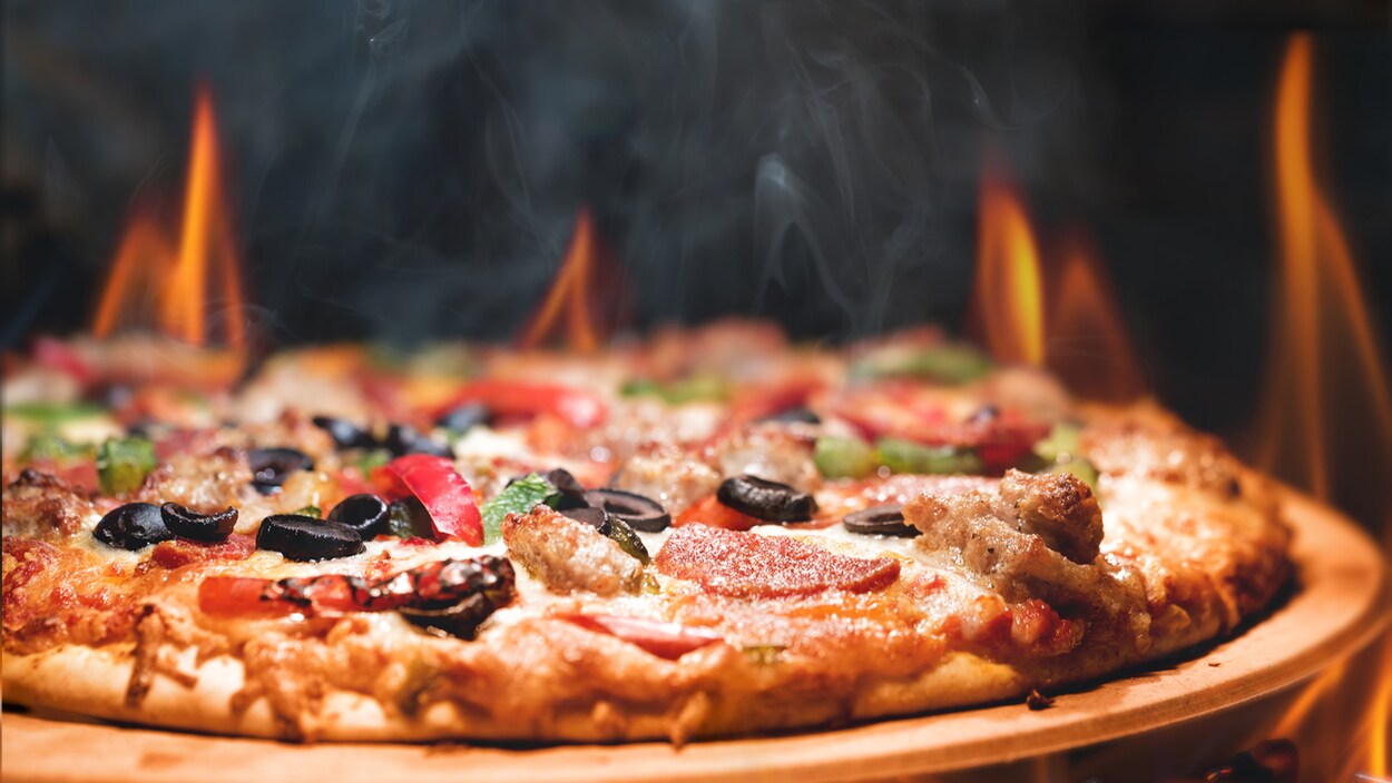 Une pizza dans un four, avec des flammes. Une pizza dans un four, avec des flammes.