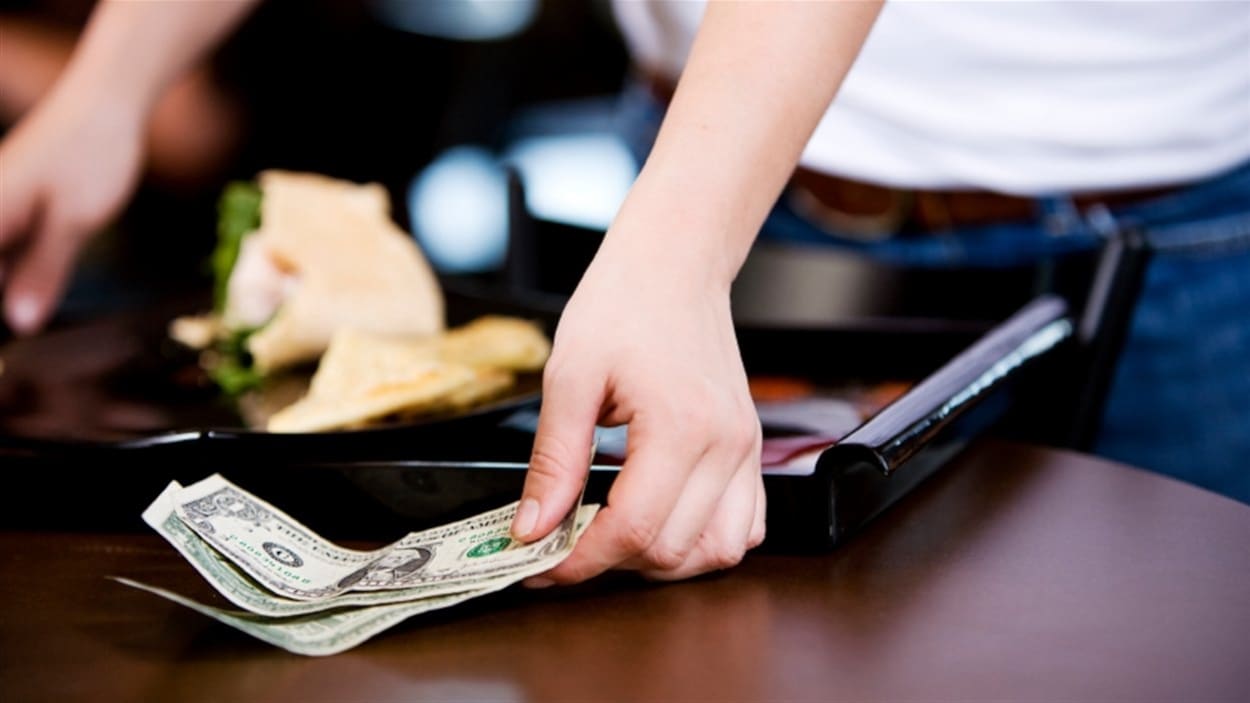Une serveuse de restaurant récupère un pourboire.