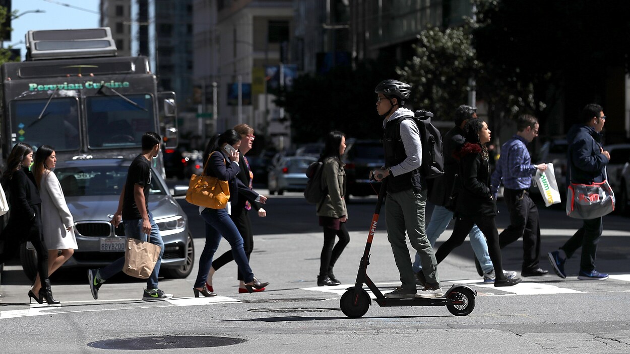 Un homme se balade à trottinette à San Francisco.