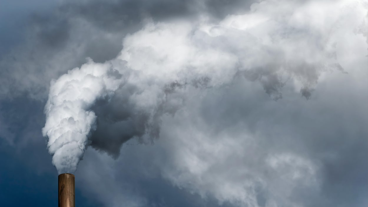 Une cheminée crache sa fumée dans le ciel.