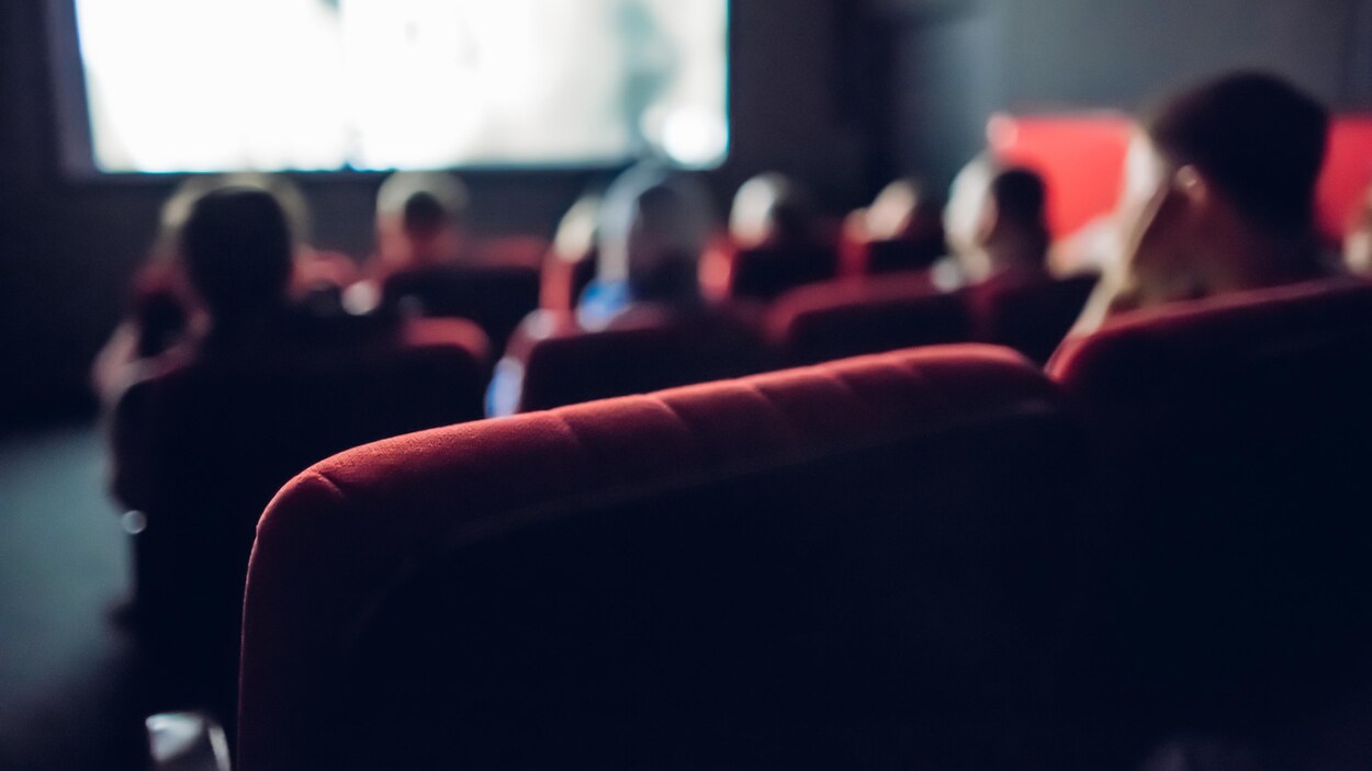 Des gens regardent un film dans une petite salle de cinéma.